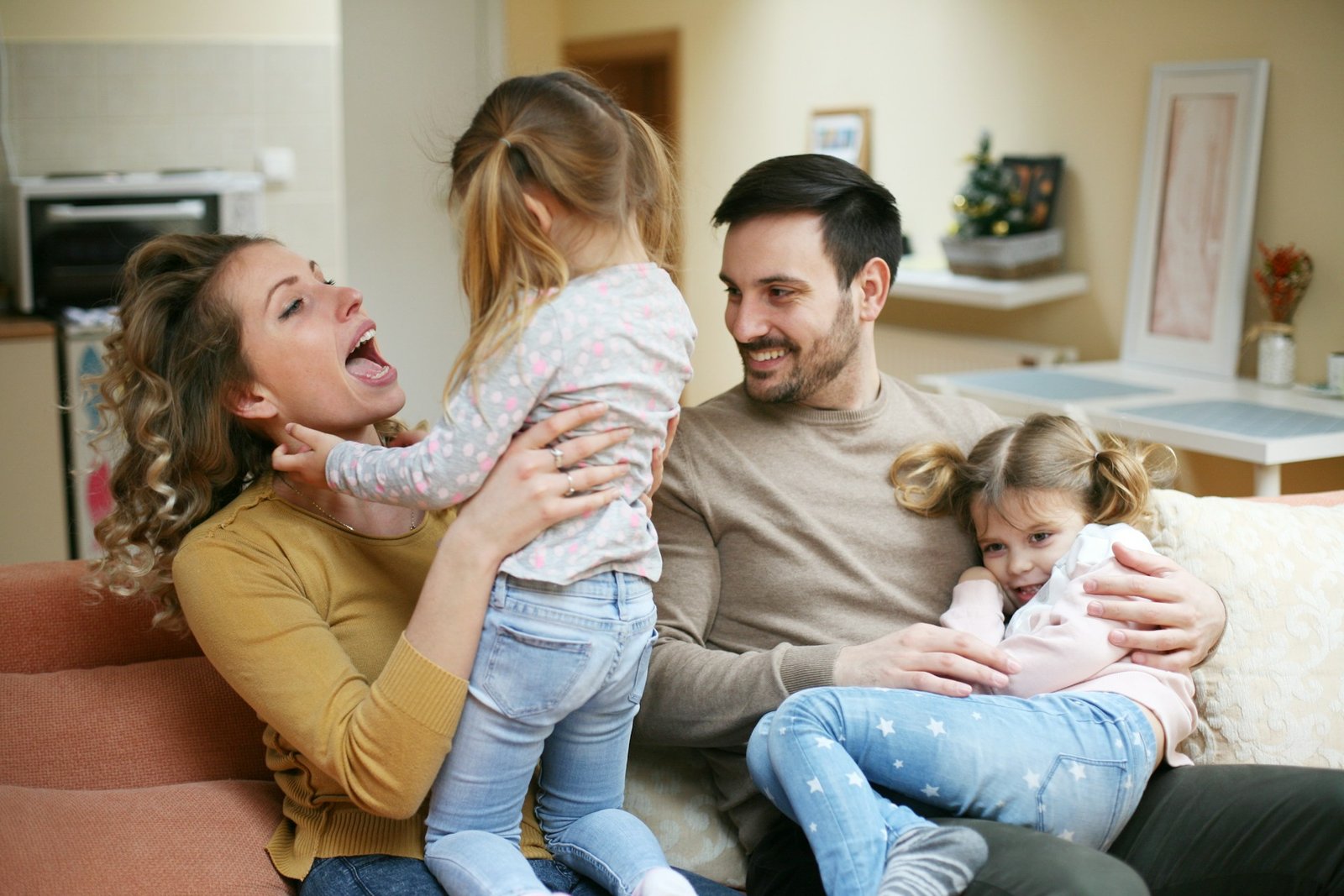 Des parents partagent un moment complice avec leurs deux filles à la maison